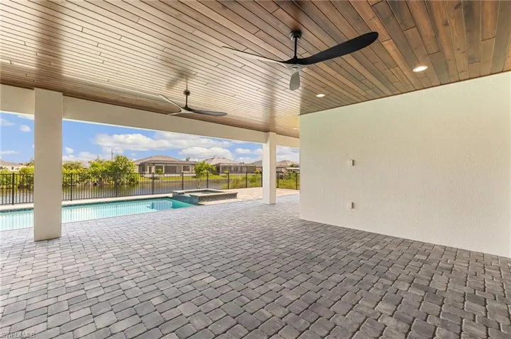 View of pool with a patio, a fenced backyard, a ceiling fan, a pool with connected hot tub, and a residential view