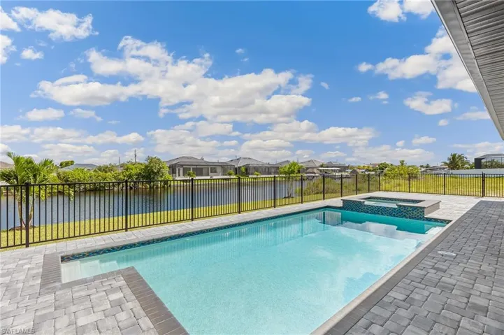 View of swimming pool with a patio area, a fenced backyard, a residential view, a water view, and a pool with connected hot tub