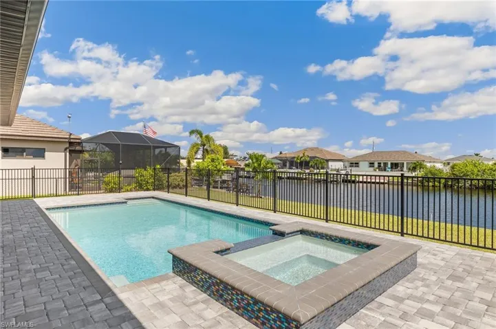 View of pool with a residential view, a water view, a fenced backyard, and a pool with connected hot tub