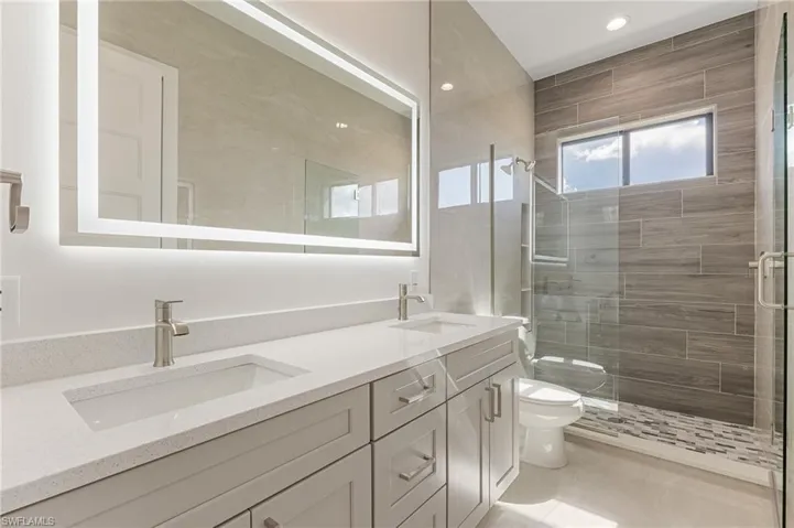 Bathroom featuring a shower stall, double vanity, and recessed lighting