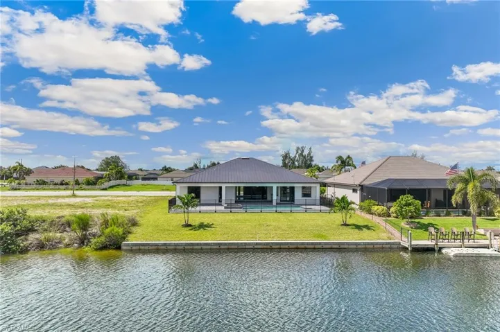 Rear view of house featuring a patio, a water view, a yard, and a metal roof