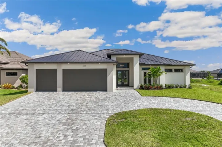 View of front of property featuring decorative driveway, a front yard, an attached garage, and stucco siding
