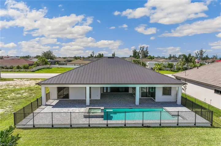 Rear view of property with a patio, a residential view, stucco siding, and a metal roof