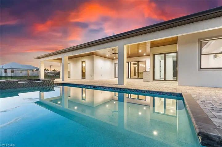 Pool at dusk with a patio area, a ceiling fan, and a pool with connected hot tub