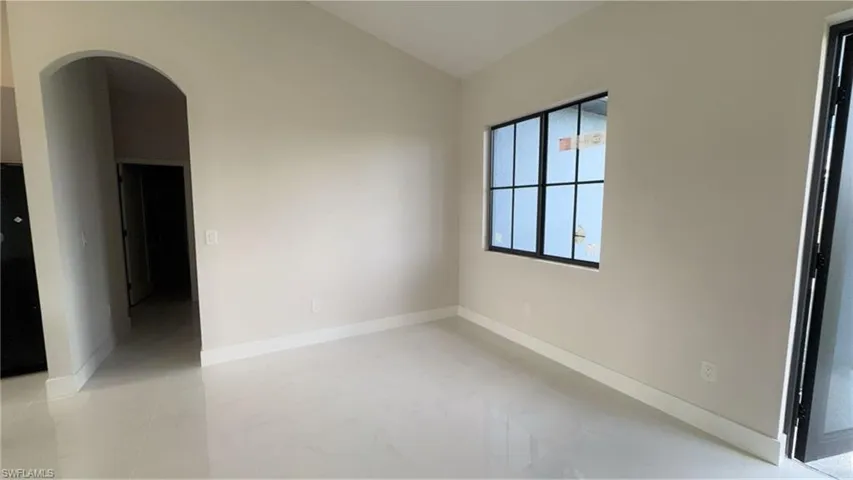 Spare room featuring arched walkways and lofted ceiling