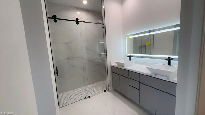 Bathroom featuring a sink and a marble finish shower