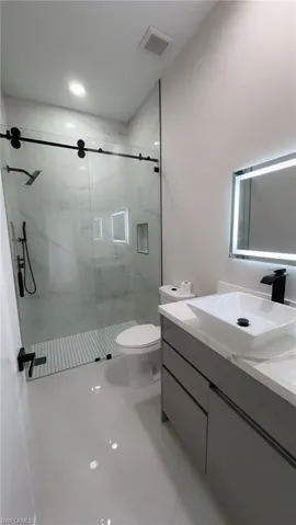 Bathroom with vanity, a marble finish shower, and recessed lighting