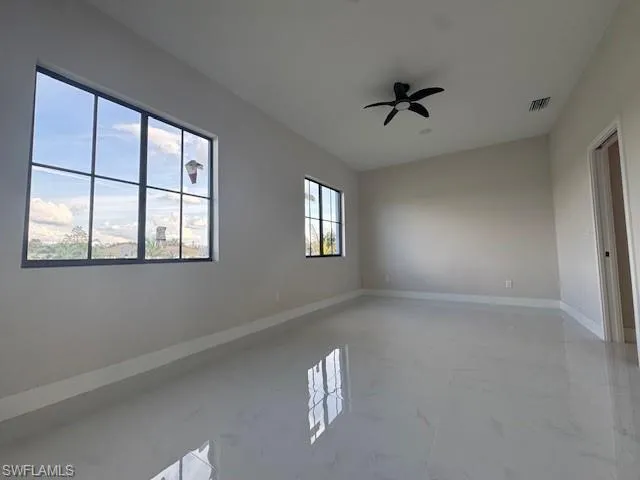 Spare room featuring light marble finish flooring and a ceiling fan