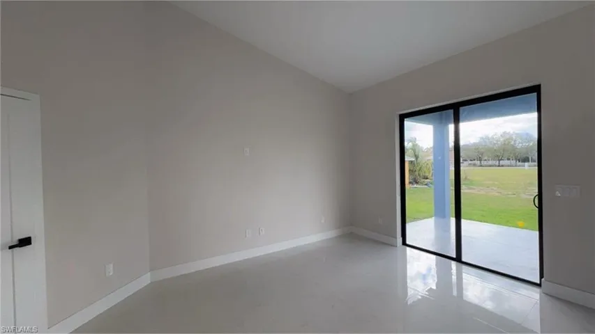 Empty room with vaulted ceiling and baseboards
