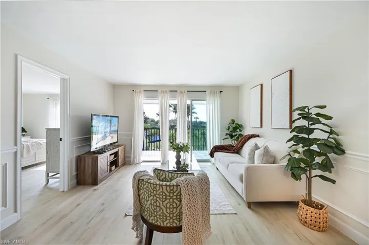 Living area featuring wainscoting, a decorative wall, and light wood-style floors