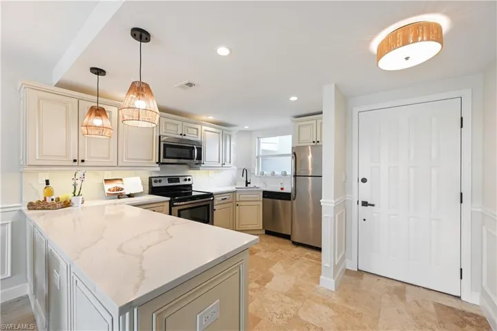 Kitchen with stainless steel appliances, a peninsula, and cream cabinets