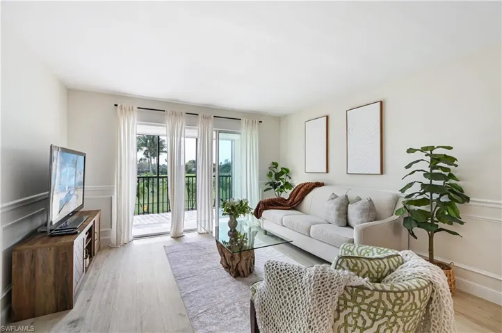 Living area with a decorative wall, wainscoting, and light wood-style floors