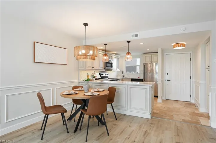 Dining area featuring a decorative wall, wainscoting, and light wood-style floors