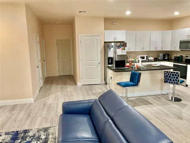Kitchen with light wood-type flooring, appliances with stainless steel finishes, white cabinets, and a breakfast bar