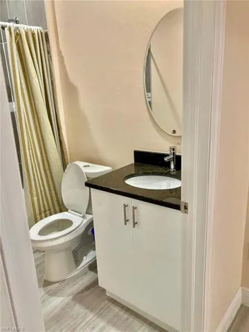 Bathroom featuring vanity, toilet, a shower with curtain, and hardwood / wood-style flooring