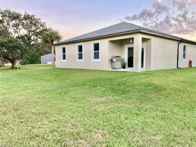 Back house at dusk featuring a lawn