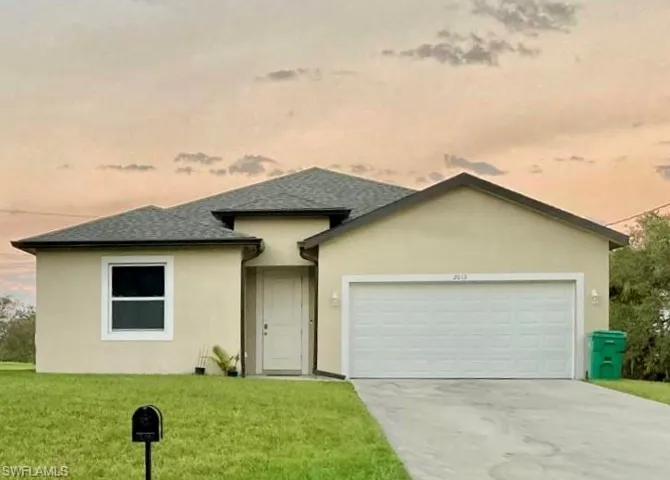 View of front of house featuring a garage and a yard