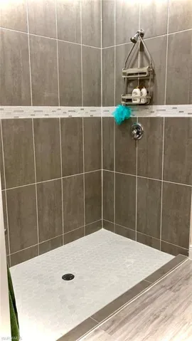 Bathroom featuring tiled shower and wood-type flooring