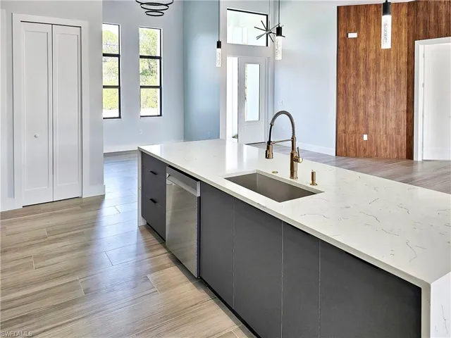 Kitchen featuring dishwasher, pendant lighting, light wood-style flooring, modern cabinets, and a sink