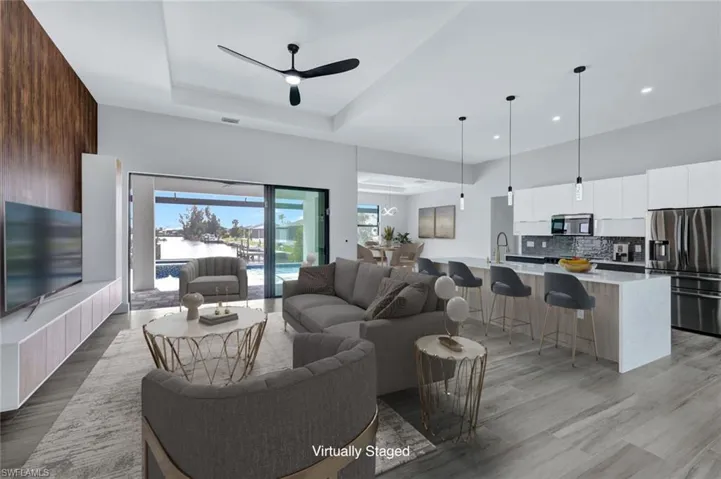 Living room featuring a ceiling fan, light wood-style flooring, recessed lighting, a tray ceiling, and a towering ceiling
