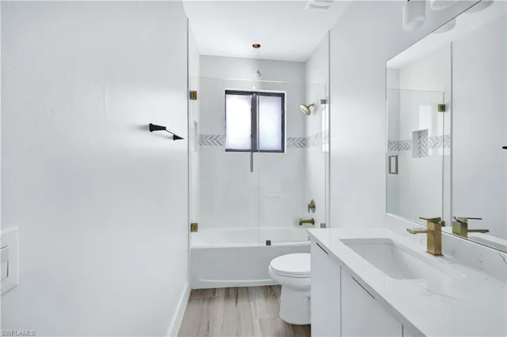 Full bathroom with toilet, vanity, bathing tub / shower combination, and wood finished floors