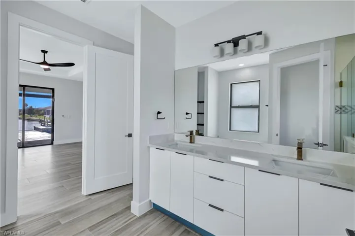 Full bath with double vanity, ceiling fan, a sink, and wood finished floors
