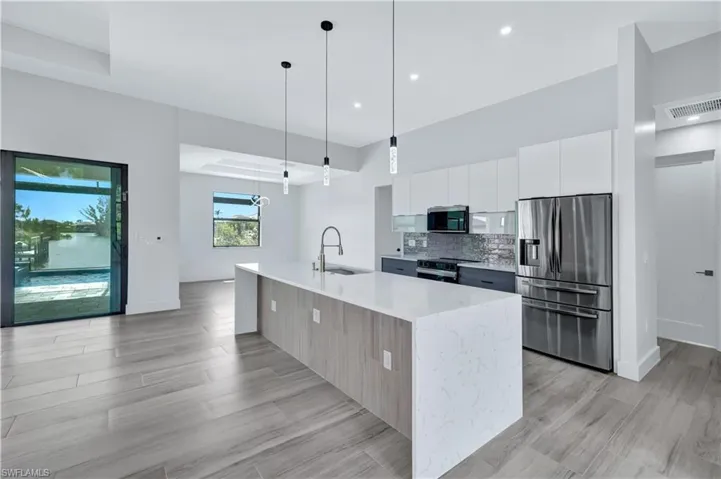 Kitchen with tasteful backsplash, appliances with stainless steel finishes, modern cabinets, visible vents, and white cabinets