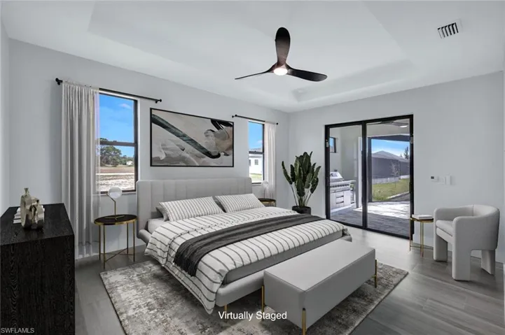 Bedroom with a tray ceiling, visible vents, wood finished floors, and access to exterior