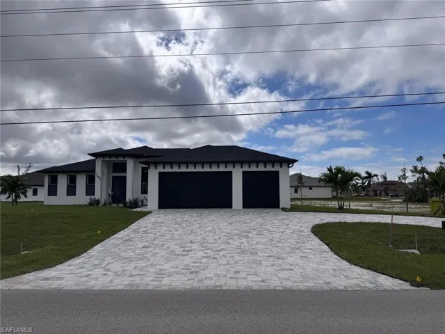 Prairie-style home with decorative driveway, a front lawn, and stucco siding