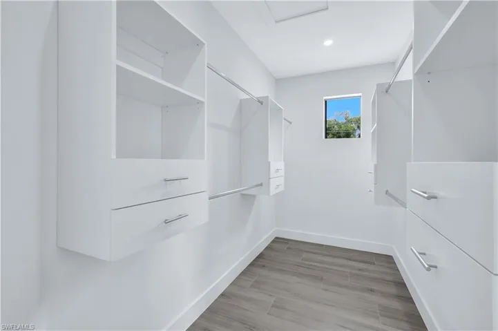 Walk in closet featuring attic access and light wood-type flooring