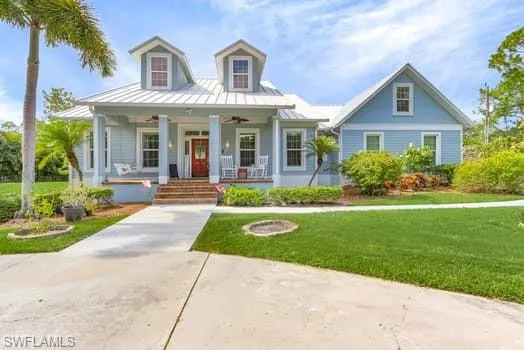 View of front of house featuring metal roof, a front yard, covered porch, and a standing seam roof
