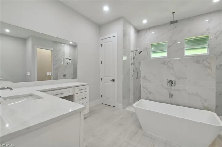 Bathroom with tile flooring, vanity, and a bath