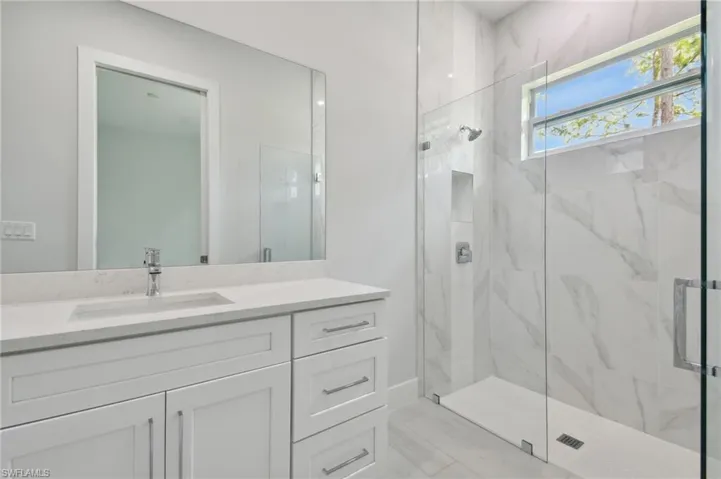 Bathroom featuring a shower with shower door and vanity with extensive cabinet space