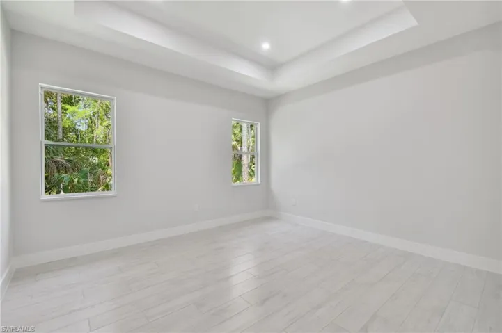 Unfurnished room featuring a tray ceiling and light wood-type flooring