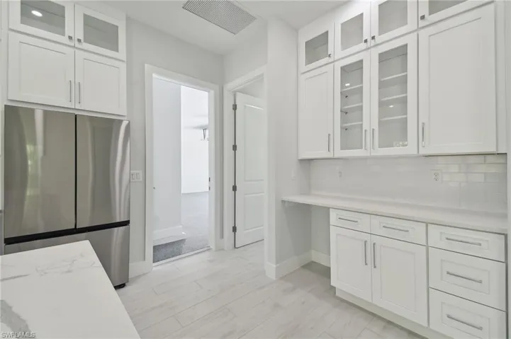 Kitchen featuring light hardwood / wood-style floors, white cabinets, backsplash, and stainless steel refrigerator