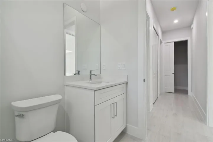 Bathroom with hardwood / wood-style flooring, vanity, and toilet