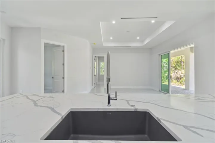 Kitchen with light stone countertops and a tray ceiling