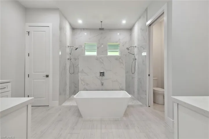 Full bathroom with tile walls, toilet, tile floors, vanity, and plus walk in shower