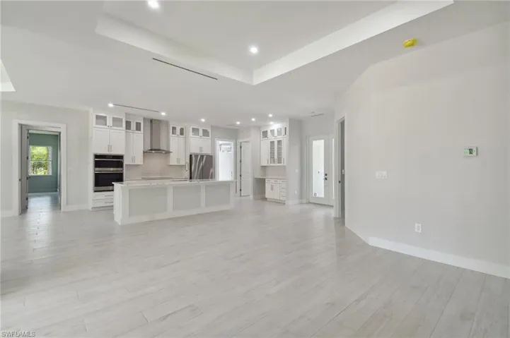 Unfurnished living room featuring light hardwood / wood-style flooring and a raised ceiling