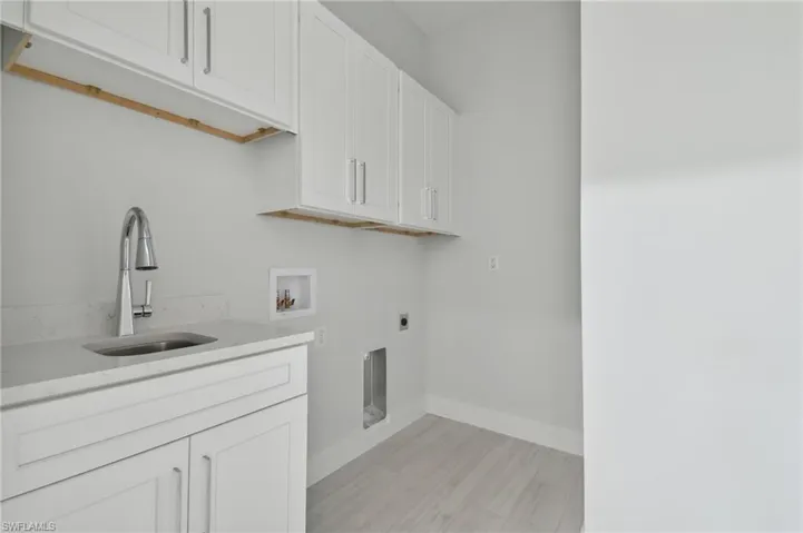 Laundry room with cabinets, light hardwood / wood-style flooring, hookup for an electric dryer, hookup for a washing machine, and sink