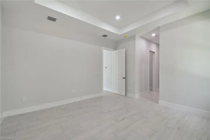 Spare room featuring a tray ceiling and light hardwood / wood-style flooring