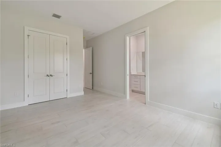 Unfurnished bedroom with a closet, light hardwood / wood-style flooring, and ensuite bath