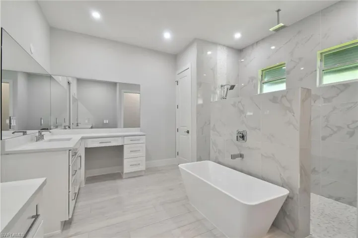 Bathroom featuring tile flooring, shower with separate bathtub, and vanity