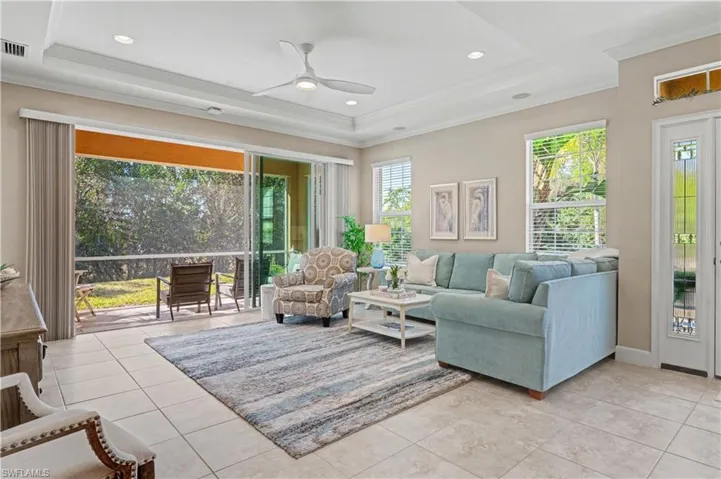 Living area with a ceiling fan, crown molding, a tray ceiling, recessed lighting, and light tile patterned floors