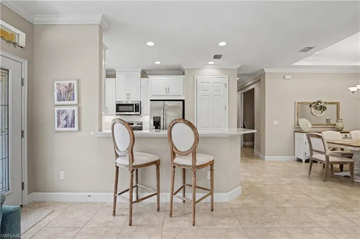 Kitchen with a breakfast bar area, a peninsula, stainless steel appliances, ornamental molding, and backsplash