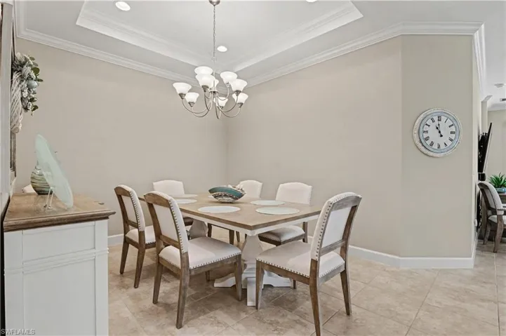 Dining space featuring ornamental molding, hanging lights, and a raised ceiling