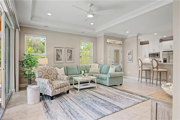 Living room with a ceiling fan, plenty of natural light, recessed lighting, light tile patterned flooring, and ornamental molding
