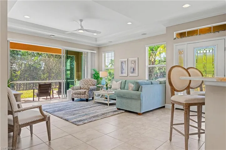 Living area featuring crown molding, ceiling fan, light tile patterned floors, recessed lighting, and a tray ceiling