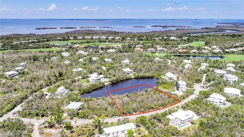 Aerial view of residential area with property parcel outlined and a nearby body of water