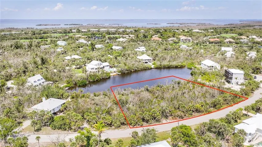 Aerial view of residential area featuring a large body of water and property parcel outlined
